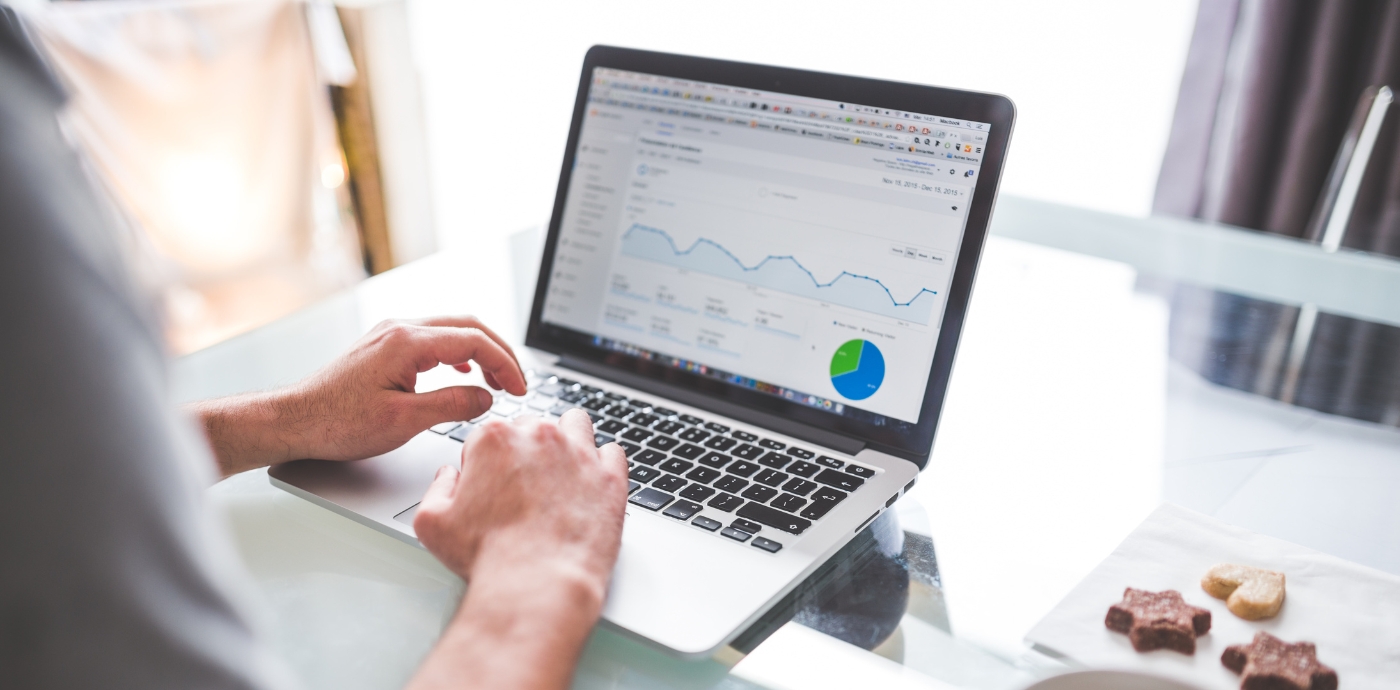 Over shoulder view of man looking at analytics on a laptop