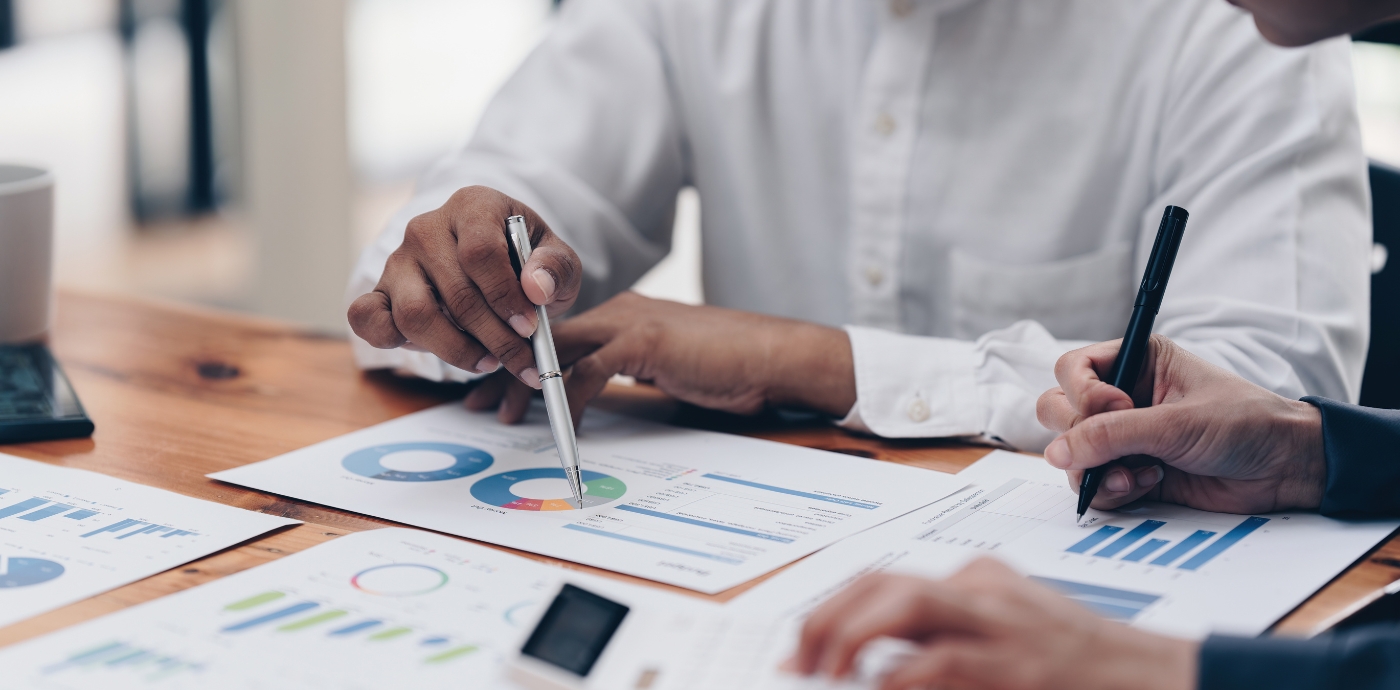 Two people looking at reports with pie charts and data