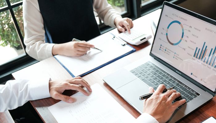 Two people looking at a budget report on a laptop