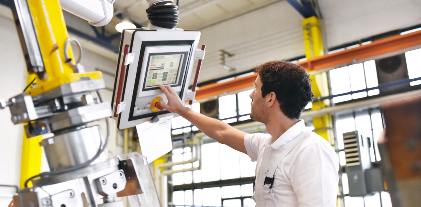 Man working in manufacturing plant with robotic machine