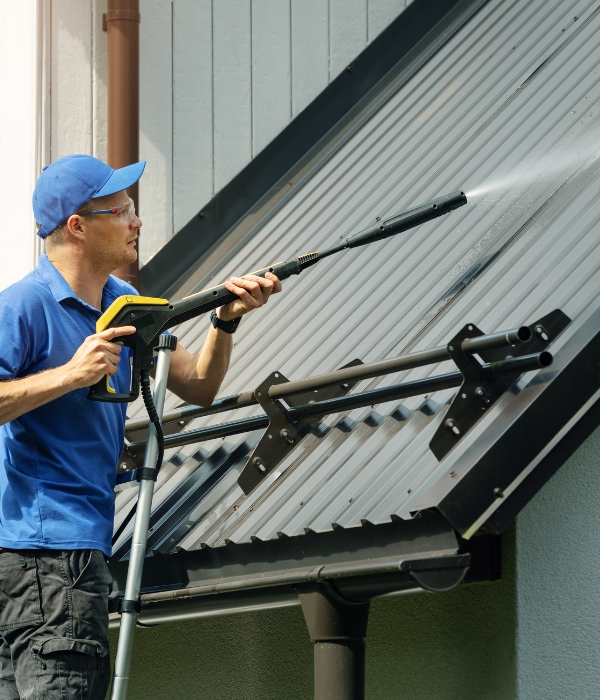 Man pressure washing a roof