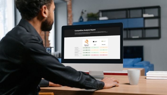 Man looking at computer screen with image of ROAR! Competitive Analysis Report Tool