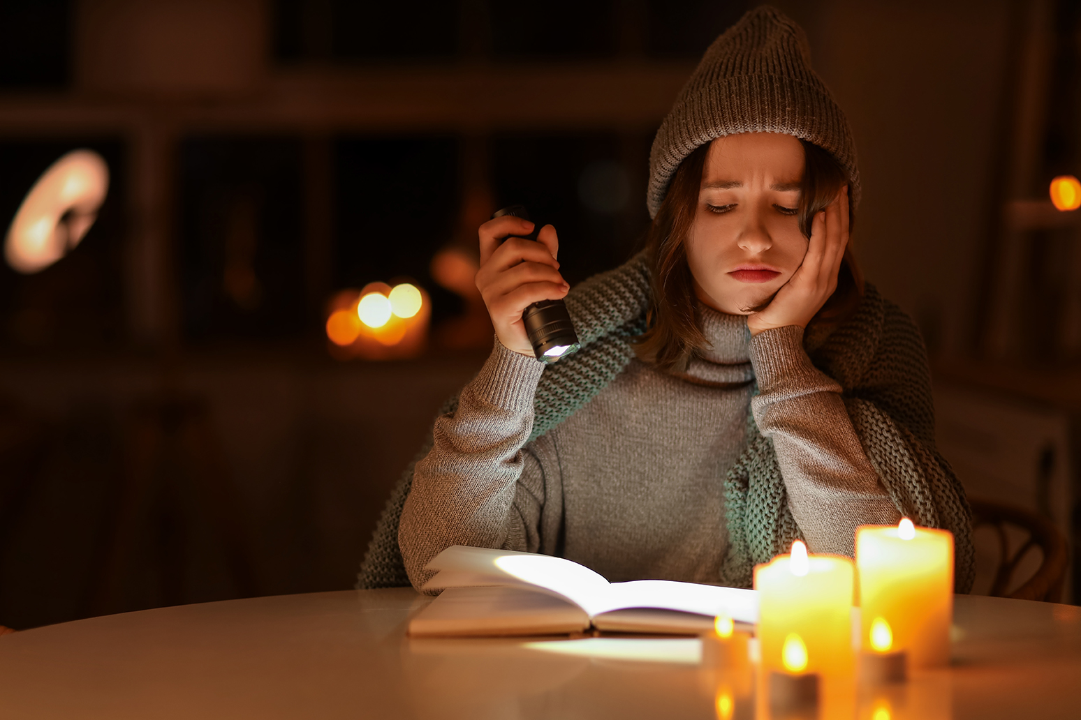 Young,Woman,With,Flashlight,Reading,Book,At,Table,In,Kitchen